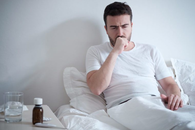  Man feeling bad lying in the bed and coughing