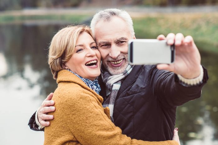 Close-up portrait of happy mature couple taking selfie in autumn park