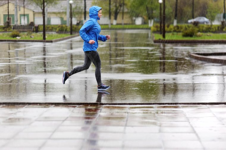Runner woman running in Park in the rain. Jogging training for marathon.