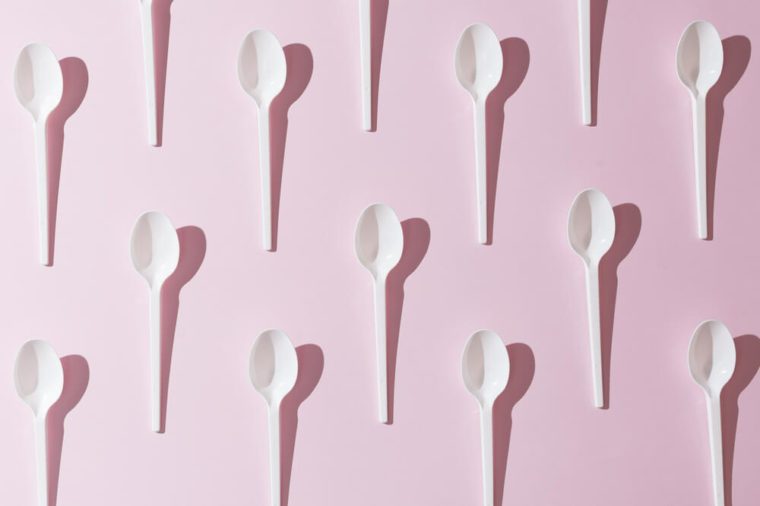 Plastic white spoons on pink background