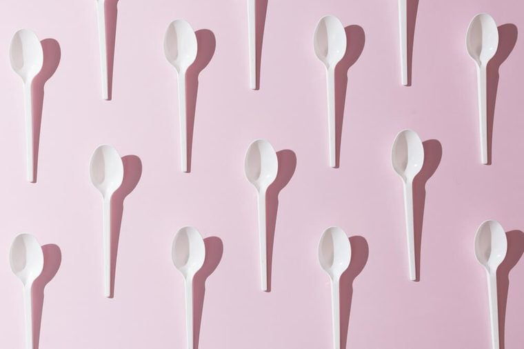 Plastic white spoons on pink background