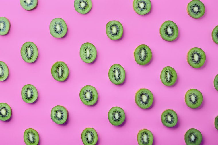 Colorful fruit pattern of fresh kiwi slices on pink background. From top view