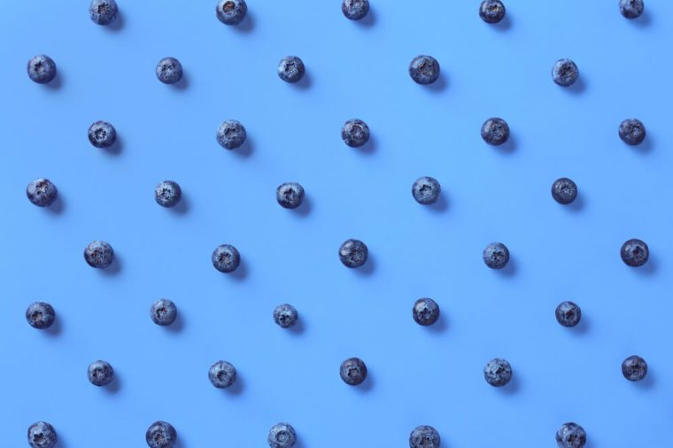Colorful pattern of blueberries on blue background. From top view