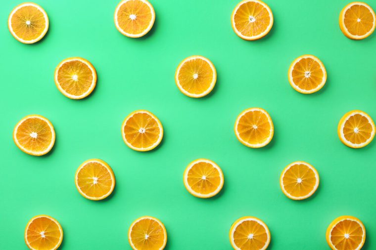 Colorful fruit pattern of fresh orange slices on green background. From top view
