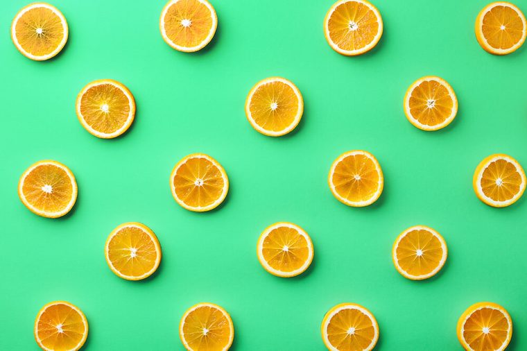 Colorful fruit pattern of fresh orange slices on green background. From top view