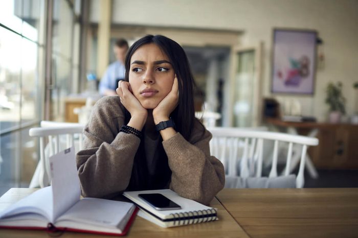 Young student girl dressed in casual wear worried about coursework project thinking about researchers sitting in cafe interior, female manager confused with planning working schedule making solution