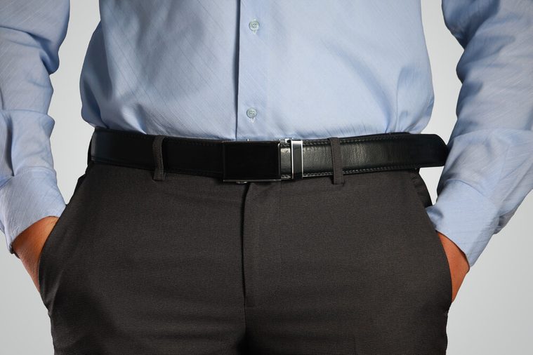 Photo image closeup shot of male waist with hands in pocket dressed in black pants, belt, blue shirt. Formal wear