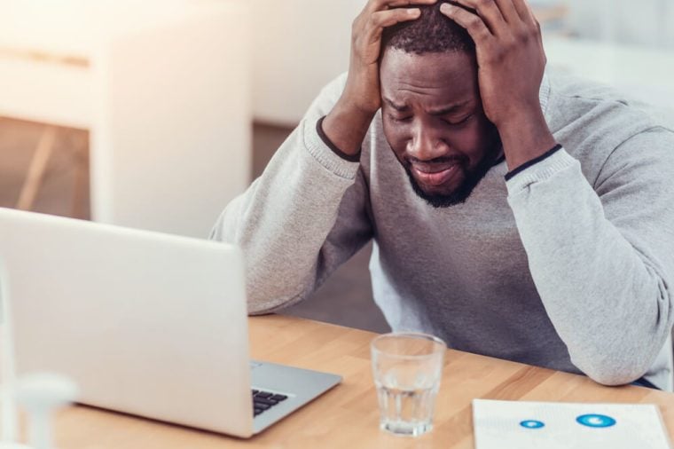 Stressed African American guy crying at work