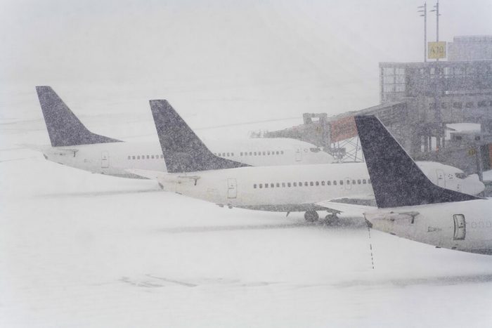 Blizzard on an international airport, airplanes waiting in the snow, free copy space