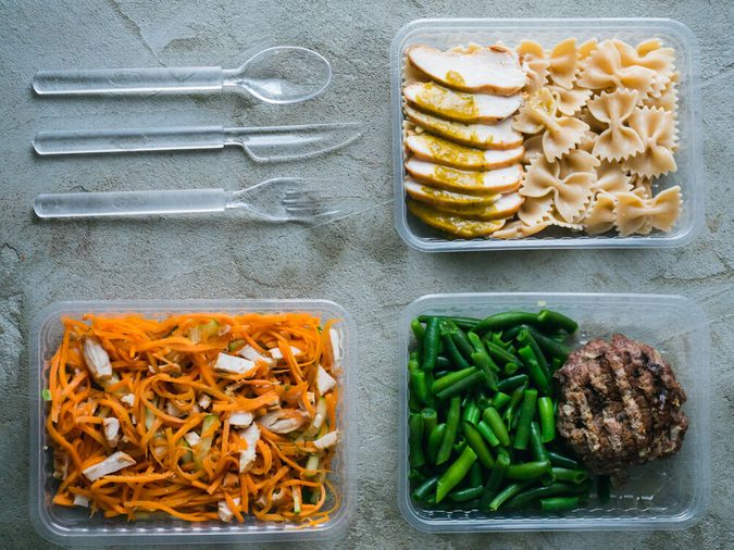 Food in plastic boxes, Daily meal plan delivery service. Fitness food cooked: beef with green beans, pasta with chicken, carrot salad