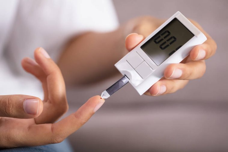 Close-up Of A Person's Hand Checking Sugar Level With Glucometer