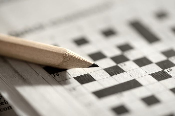 Close up view of a blank crossword puzzle grid with black and white squares and a pencil
