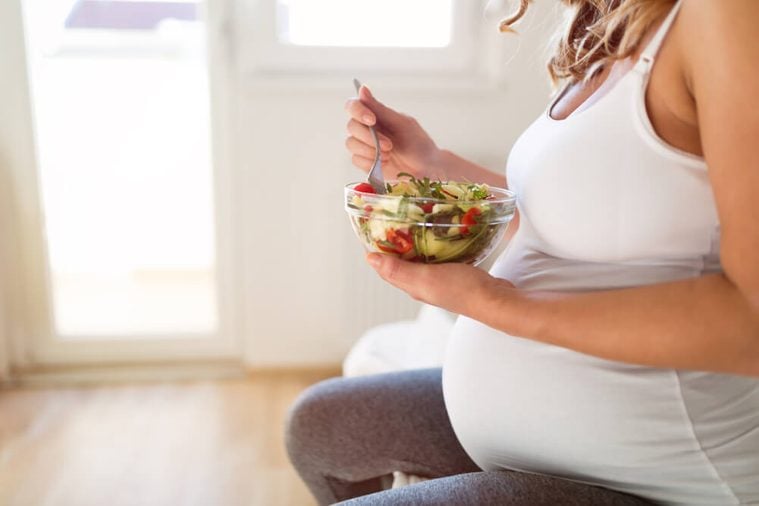 Pregnant woman eating fresh healthy salad