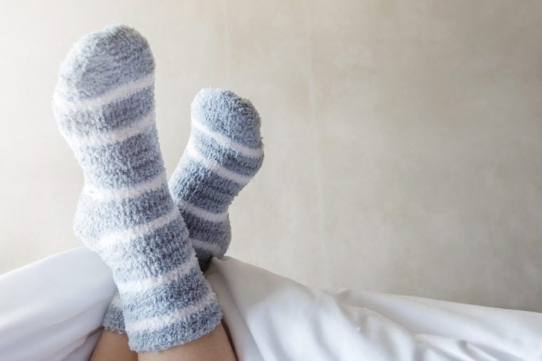 Female foot in warm Stripe wool sock ,Woman Sleeping and Relaxing in bed concept, Rare View