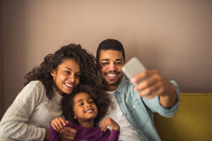 African american family taking pictures with mobile phone at home.