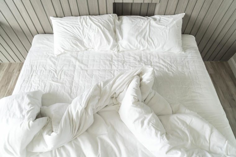 rumpled bed with white messy pillow decoration in bedroom interior