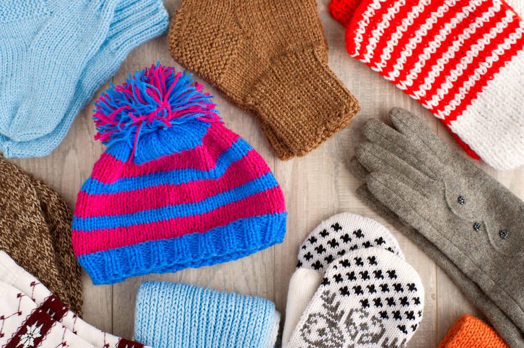 Knitted clothes. Hat, gloves, mittens, scarves for cold seasons. Warm clothes. Knitted clothes of different colors. Hat, mittens, scarves, gloves, socks from the cold. View from above.