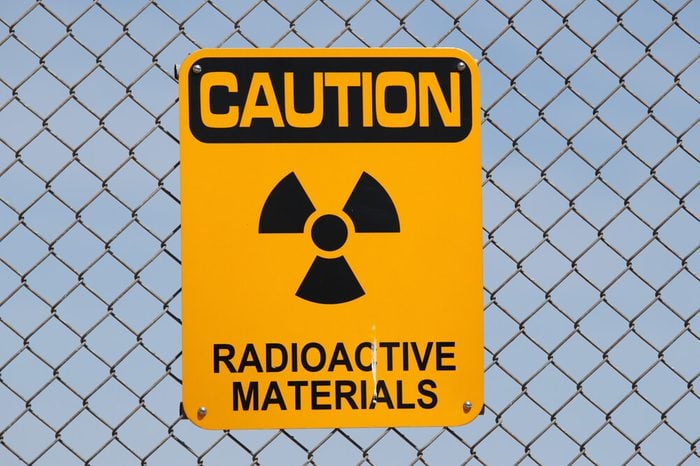 A "Caution - Radioactive Materials" sign on a fence.
