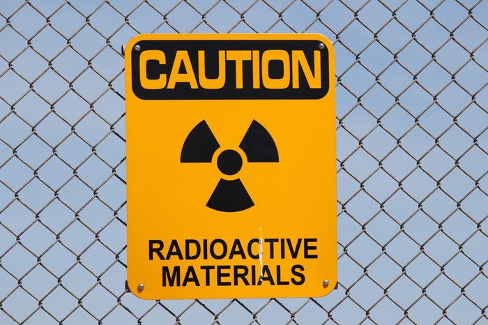 A "Caution - Radioactive Materials" sign on a fence.