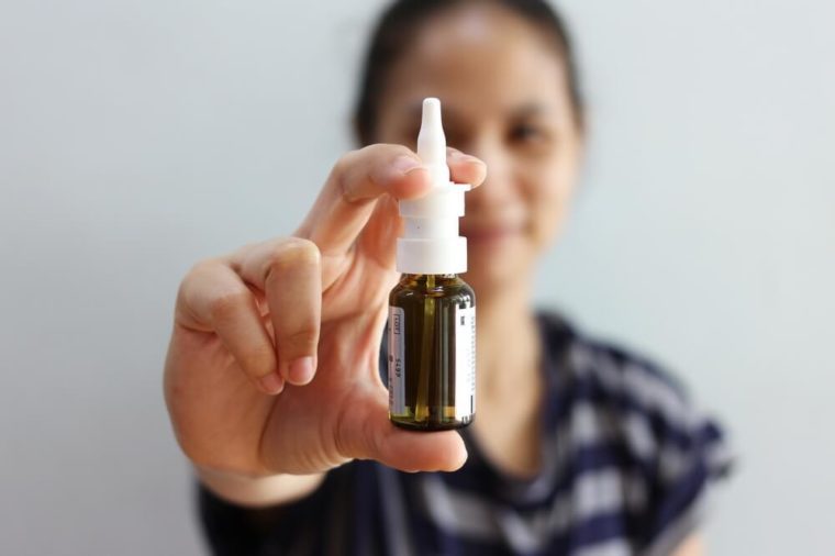  Nasal Spray, Female hand spraying nasal spray with blurred background