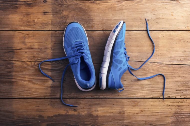 Pair of blue running shoes laid on a wooden floor background
