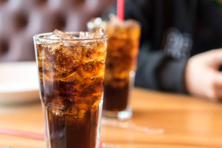 Double cool ice soft drink cola carbonated liquid fresh food with soda water, white dish on wooden table with handsome man sitting brown sofa in pizzeria restaurant.