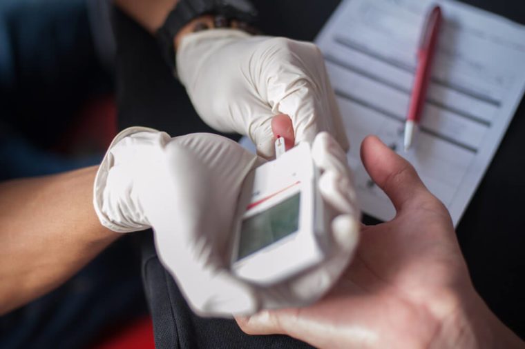 Close-up Of Doctor's Hands doing a blood test with a glucometer on the finger of a diabetes person.Close up shot with selective focus.