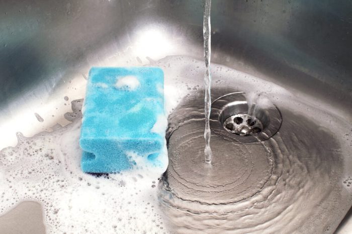 sponge in kitchen sink under running water