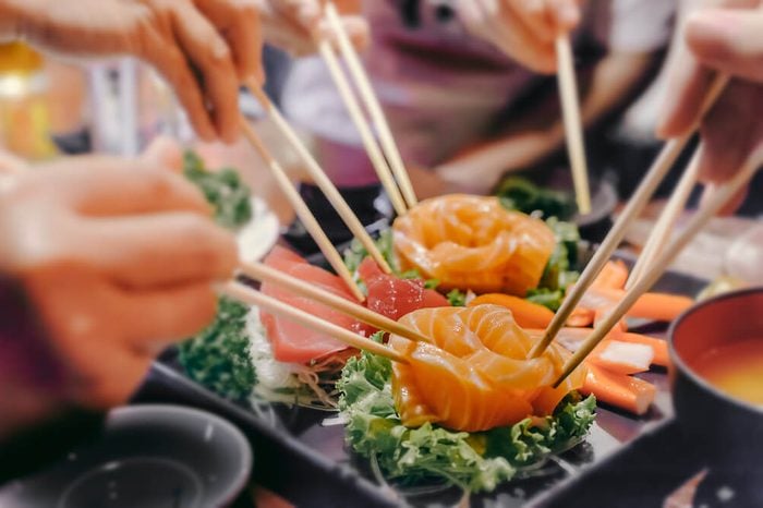 Asian people eating sashimi set in Asian restaurant