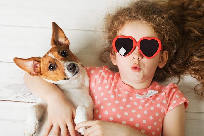 a girl in sunglasses lays on the floor with her cute puppy