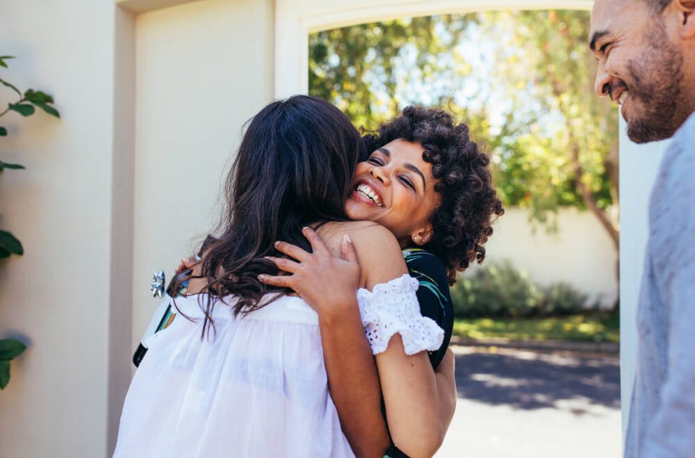 African woman greeting female friend for having a new house. Smiling young woman congratulating her friend. Couple welcoming friend for housewarming party.