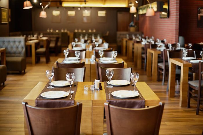 Roomy hall in restaurant with wooden furniture and walls of red bricks