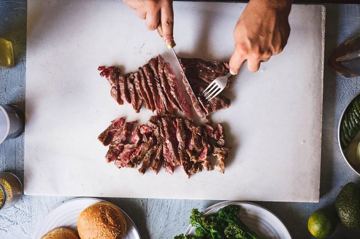Person cutting beef grill steak in sliced over marble kitchen table overhead hot beef grilled steak 