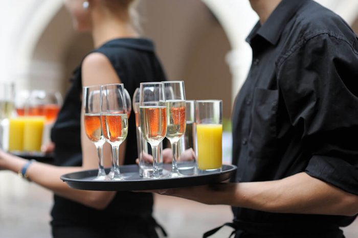 Waiter with dish of champagne, wine and juice glasses
