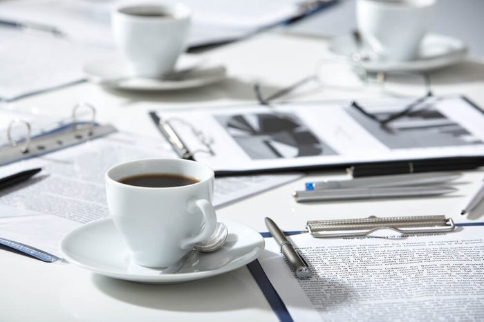 Close-up of documents, pen, cup of coffee on the table