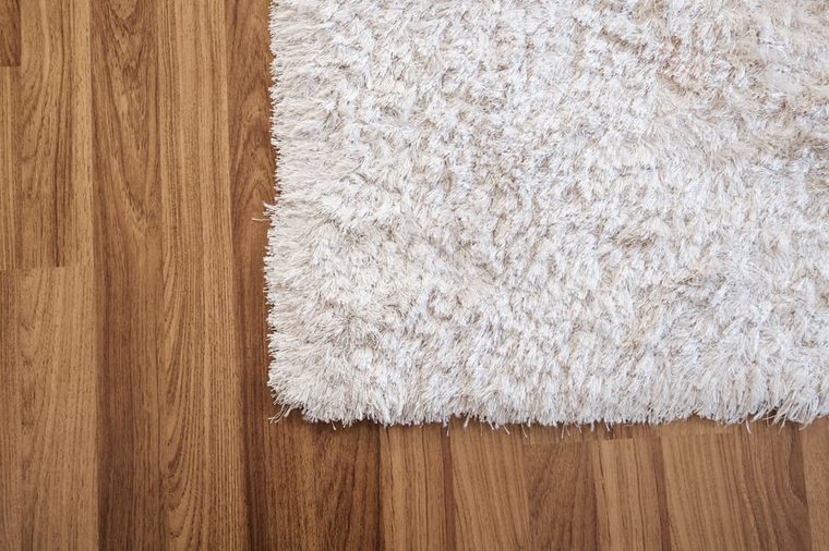 Close-up white carpet on laminate wood floor in living room, interior decoration