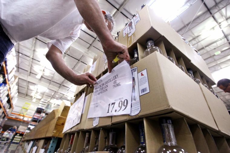 Store wine steward Robert Shelden places price signs on boxes of gin at a Costco warehouse store, in Seattle. Private retailers begin selling spirits for the first time under a voter-approved initiative kicking the state out of the liquor business. The initiative allows stores larger than 10,000 square feet and some smaller stores to sell hard alcohol