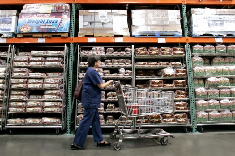 A shopper walks past shelves of bread at a Seattle Costco store . Costco Wholesale Corp. reported a 32 percent jump in its fiscal third-quarter profit Thursday, topping Wall Street expectations, as cash-squeezed customers flocked to its warehouse clubs in search of bargains on food and toiletries