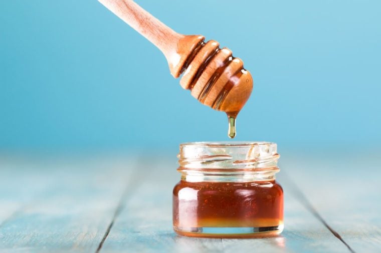 Honey in jar with honey dipper on blue background healthy food