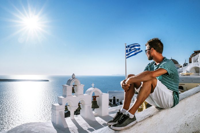 Santorini Oia Greece Young man looking out over the village on a bright summer day at the white washed bouldings of Santorini