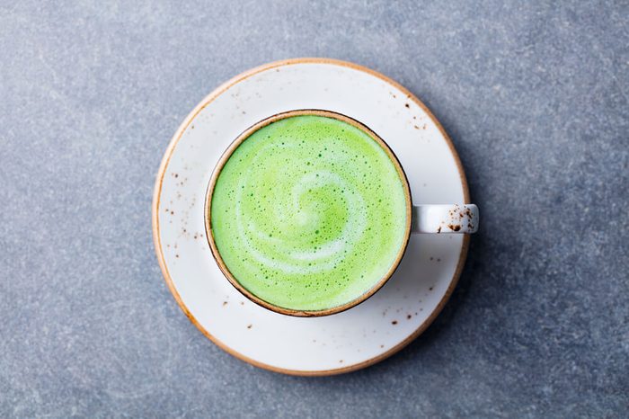Matcha, green tea latte in a cup. Grey stone background. Top view.