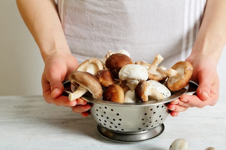 Female chef hands holding a colander with shiitake mushrooms