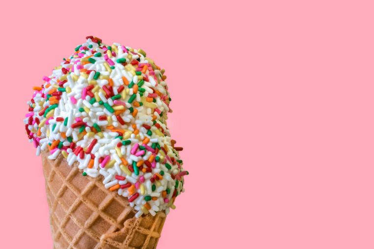 Ice Cream Scoops with Colored Sprinkles in a Waffle Cone on a Light Pink Background