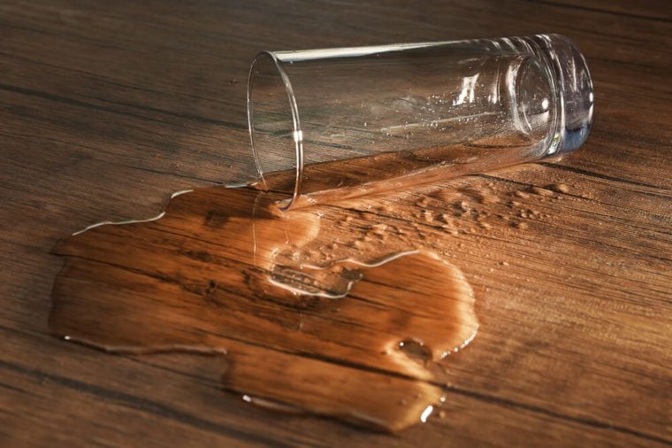 Glass of water spilled on wooden background