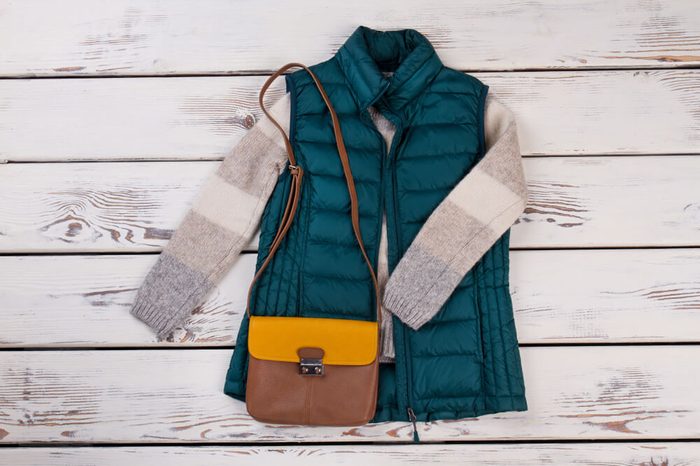 Pairing of turquoise vest and brown bag. Stylish layering of clothing for winter season. Women's fashion.