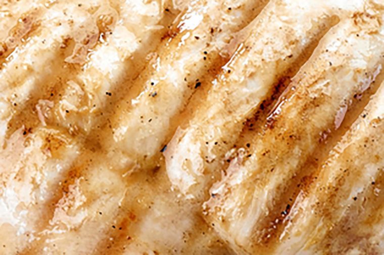 grilled chicken fillets on wooden cutting board, top view