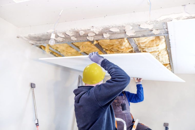 Workers assemble a suspended ceiling with drywall