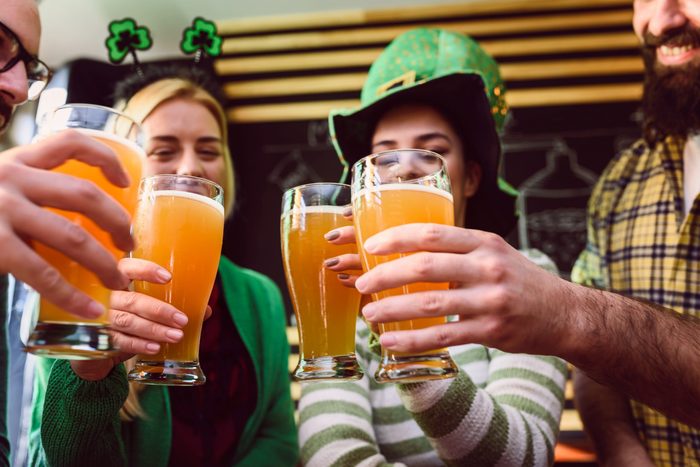 Smiling young people drinking craft beer in pub on St Patrick's Day holiday. fun facts.