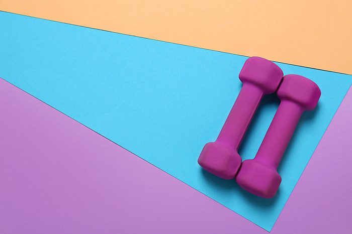Dumbbells and blank space for exercise plan on color background. Flat lay composition