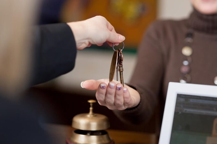 Receptionist giving room keys to customer at reception in hotel